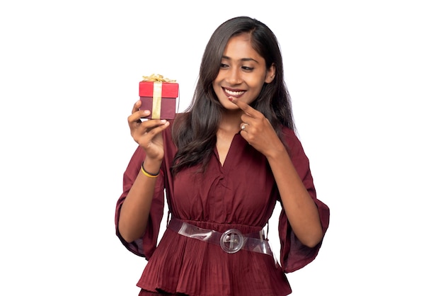 Portrait of young happy smiling Girl in red dress holding and posing with gift box on white background