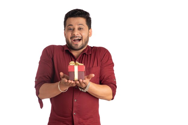 Portrait of young happy smiling handsome man holding gift box and posing on a white background