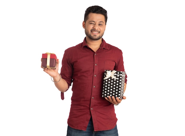 Портрет молодого счастливого улыбающегося красивого мужчины, держащего подарочную коробку и позирующего на белом фоне