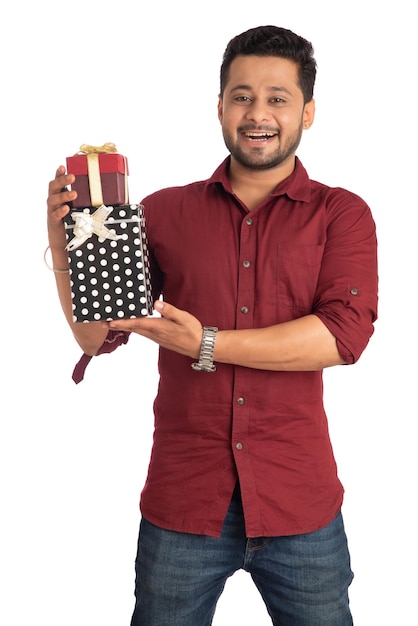 Портрет молодого счастливого улыбающегося красивого мужчины, держащего подарочную коробку и позирующего на белом фоне