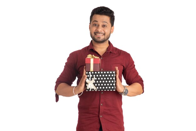 Portrait of young happy smiling handsome man holding gift box and posing on a white background