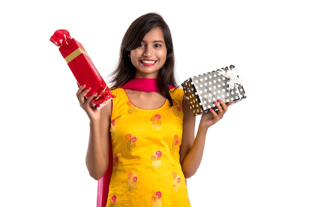 Ritratto di giovane ragazza indiana sorridente felice che tiene i contenitori di regalo su un bianco.