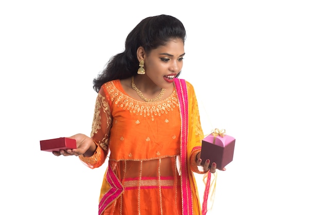 Портрет молодой счастливой улыбающейся индийской девушки, держащей подарочные коробки на белом