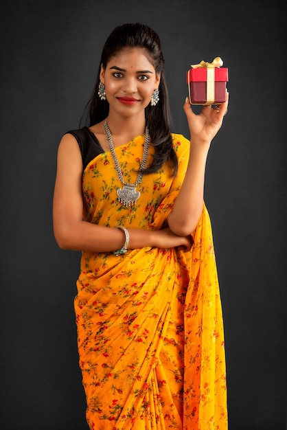 Portrait of young happy smiling woman Girl holding gift box on a grey background