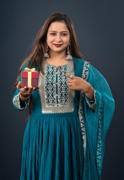 Portrait of a young happy smiling woman Girl holding gift box on a grey background