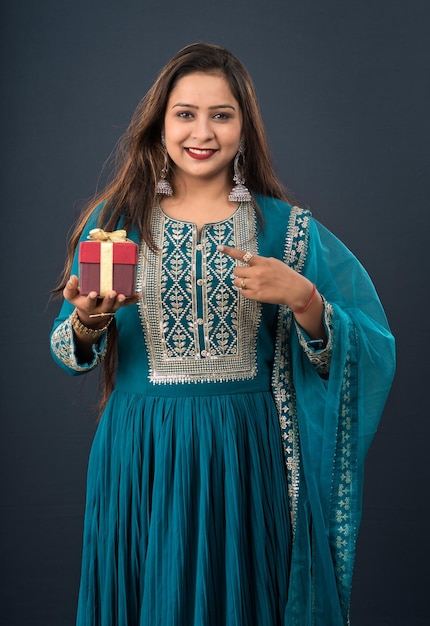 Portrait of a young happy smiling woman Girl holding gift box on a grey background