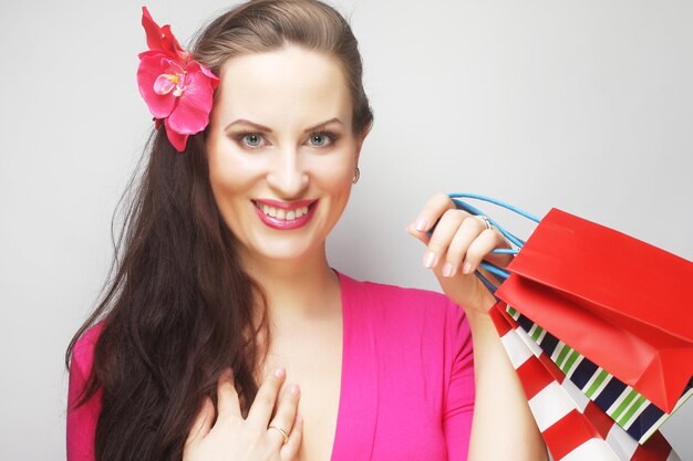 Portrait of young happy smiling woman with shopping bags, over gray background