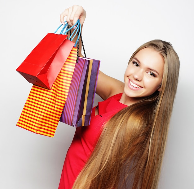 Portrait of young happy smiling woman with shopping bags, over white background