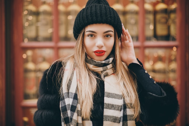 Portrait of young happy woman wearing winter clothes in french style, posing in streets