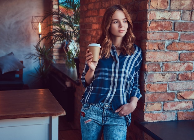 Portrait of a young hipster girl drinks morning coffee leaning a
