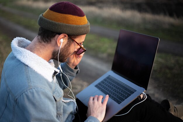 Portrait of young hipster man using laptop outdoor