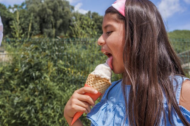 晴れた日に公園でアイスクリームコーンを食べるヒスパニック系の若い子供の肖像画