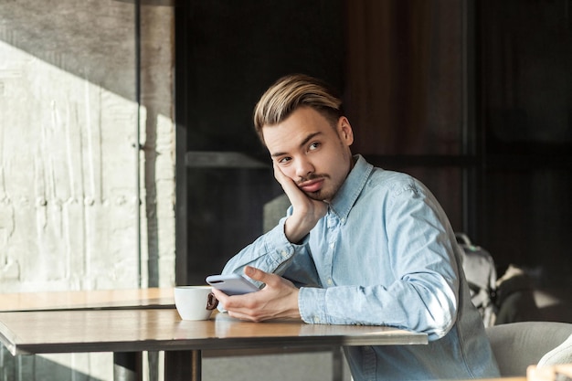 Portrait of young holding mobile phone in office