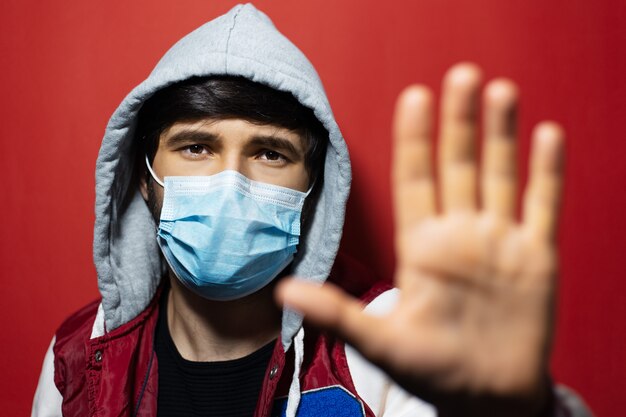 Foto ritratto di giovane uomo incappucciato che indossa la maschera di influenza medica