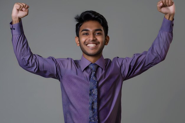 Portrait of a young indian business man celebrating success on grey background