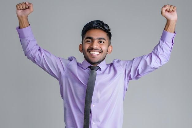 Portrait of a young indian business man celebrating success on grey background