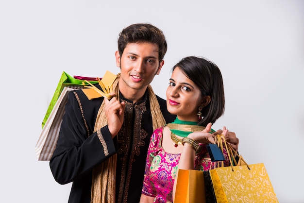 Ritratto di giovane coppia indiana con borse della spesa, isolato su sfondo bianco