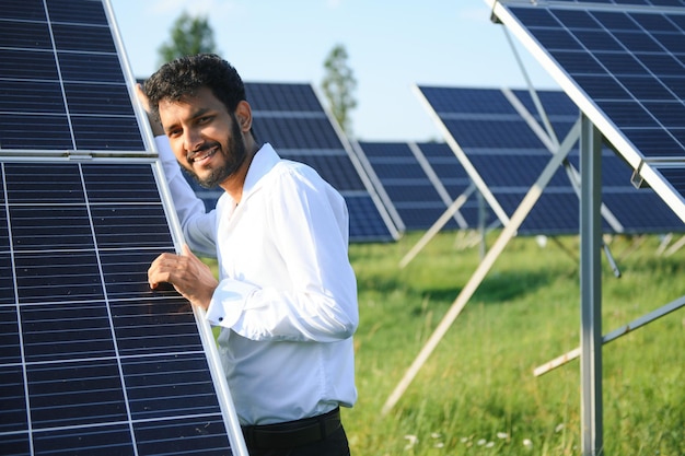 Portrait of Young indian male engineer standing near solar panels with clear blue sky background Renewable and clean energy skill india copy space