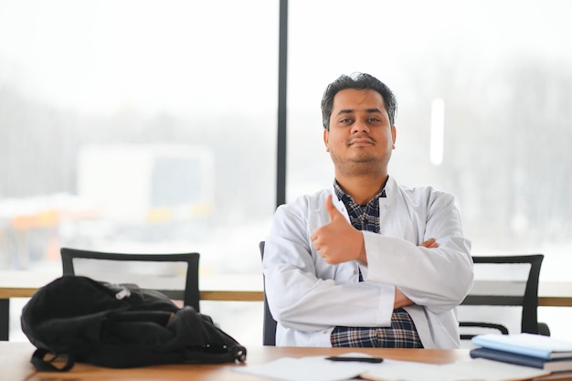 Portrait of a young Indian male medical student in a white coat waving