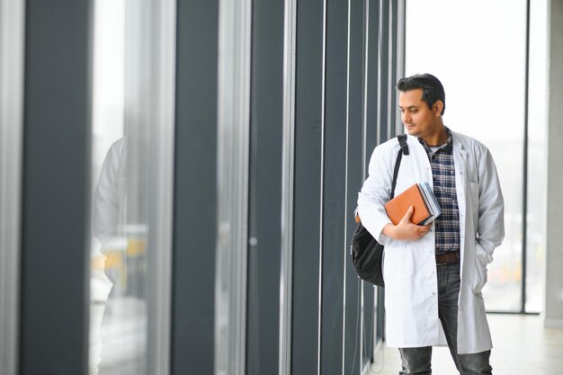 Portrait of a young Indian male medical student in a white coat waving