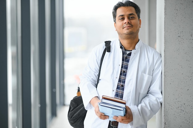 Portrait of a young Indian male medical student in a white coat waving