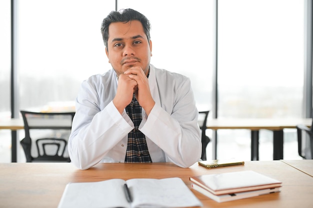 Portrait of a young Indian male medical student in a white coat waving