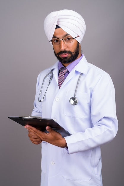 Portrait of young Indian Sikh man doctor holding clipboard