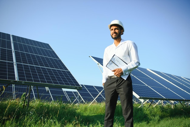 Portrait young indian technician or manager wearing formal cloths standing with solar panel renewable energy man standing crossed arm copy space