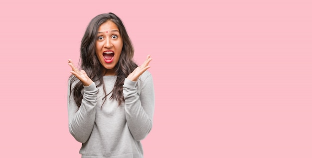 Portrait of young indian woman surprised and shocked, looking with wide eyes, excited by an offer or by a new job, win concept