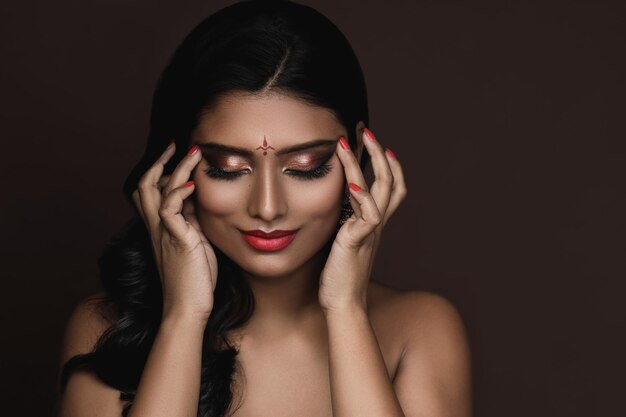 Portrait of Young Indian woman with beautiful makeup and hairstyle on brown background