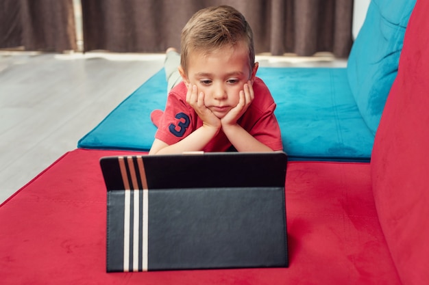 Portrait of a young kid at home watching cartoon on the laptop.