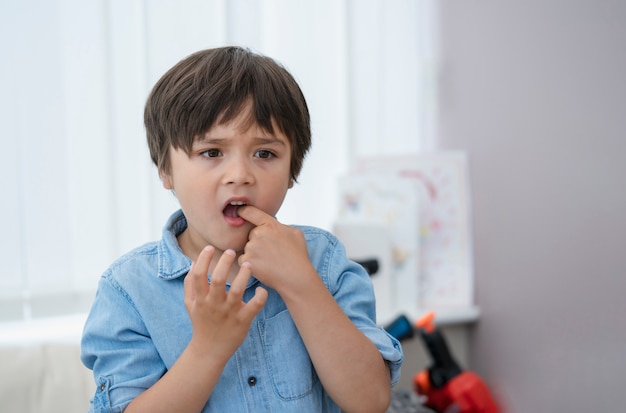 Portrait young kid putting  finger in his mounth feeling hurt from falling first tooth