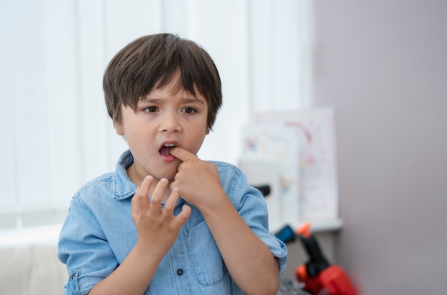 Ragazzino del ritratto che mette dito nel suo mounth sensazione ferita dalla caduta del primo dente