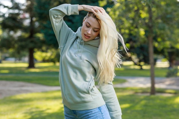 Portrait of young lady hold her hand to her hair and stand at the park