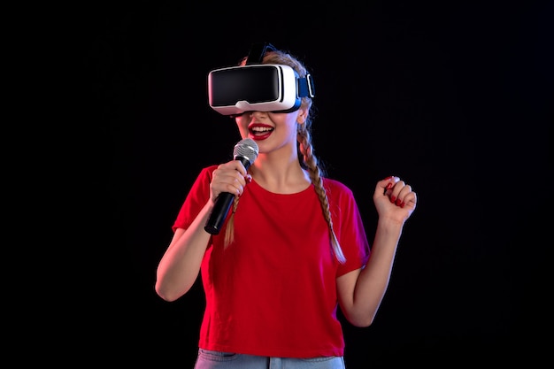 Portrait of young lady playing vr and singing on dark wall