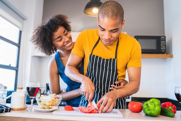 Portrait of young latin couple cooking together in the kitchen at home. Relationship, cook and lifestyle concept.