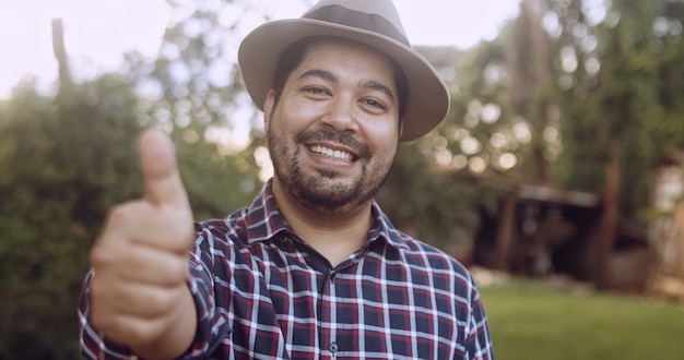 Portrait of young Latin farmer man in the casual shirt in the farm on the farm background.