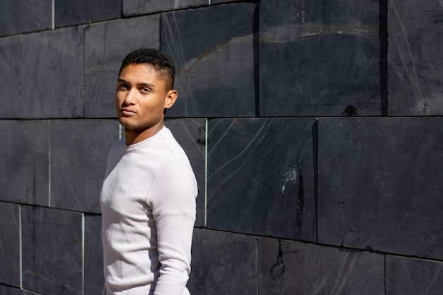 Portrait of a young latin guy on a gray wall