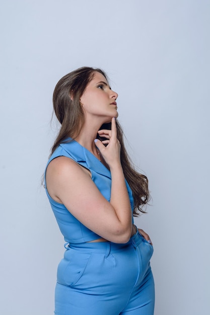 portrait of young latin woman in blue posing with hand on chin studio shot copy space