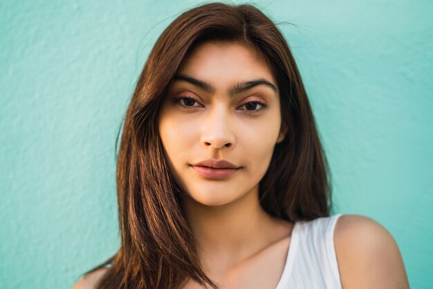 Portrait of young latin woman on light blue