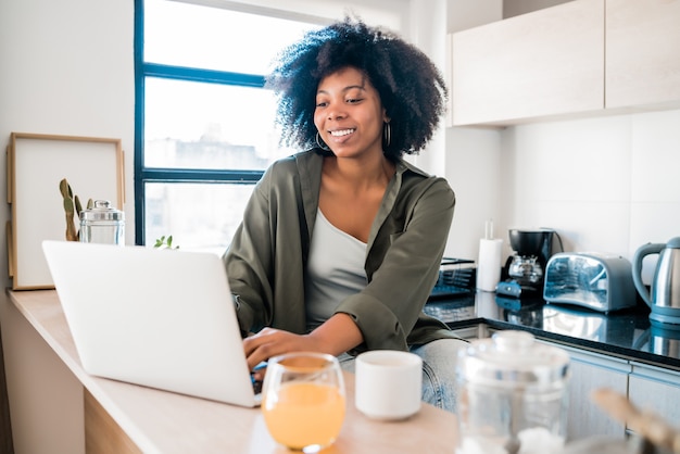 Portrait of young latin woman using laptop at home.