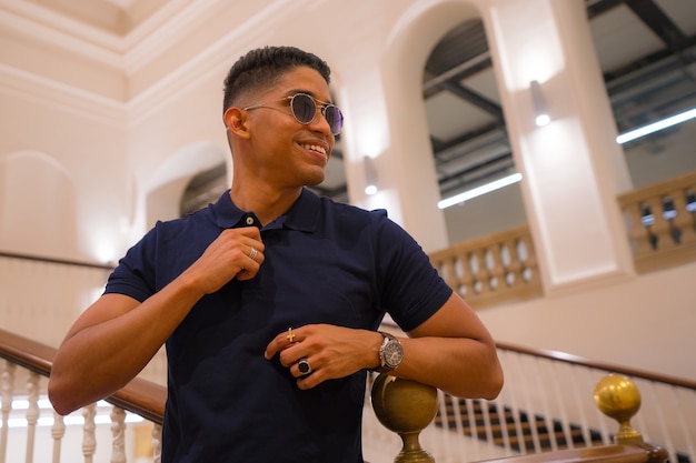 Photo portrait of a young latino man in a beautiful old building. blue polo shirt and plaid pants