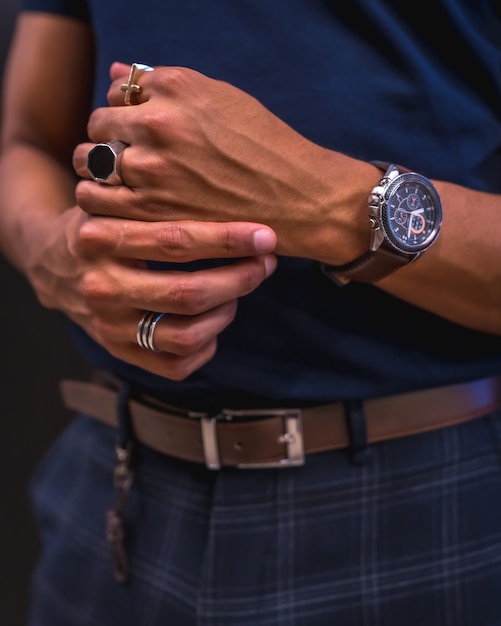 Portrait of a young Latino man on a black wall. Blue polo shirt and plaid pants