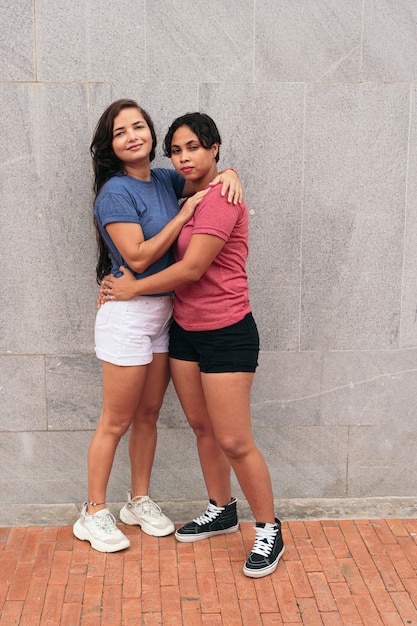 Portrait of a young lesbian couple embracing on a city street while enjoying a day together.