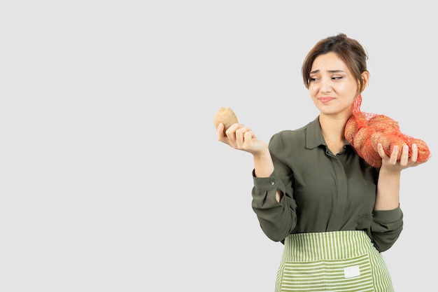 Portrait of a young lovely farmer woman holding potatoes in bag. High quality photo