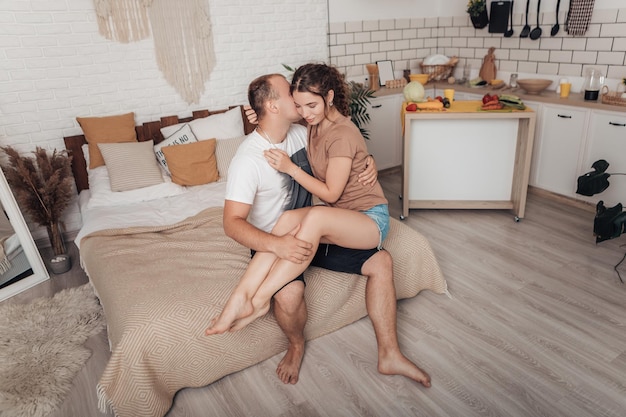 Portrait of young loving couple sitting on bed chilling and spending time together