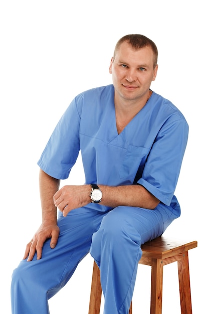 Portrait of a young male doctor in a medical surgical blue uniform against a white
