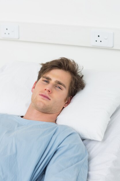 Portrait of young male patient lying in hospital bed