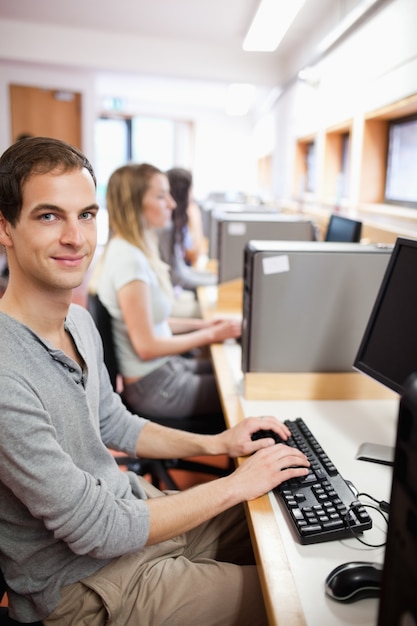 Ritratto di un giovane studente maschio in posa con un computer