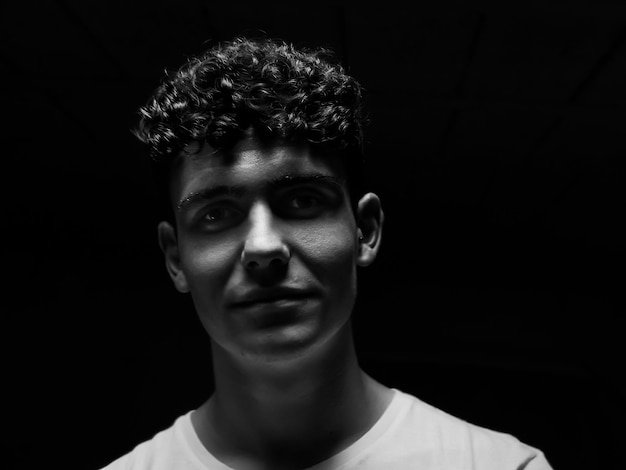 portrait of young man against black background